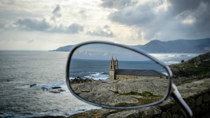 Church reflected in a motorcycle mirror overlooking the sea