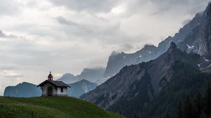 Small church on a grassy hill with mountains
