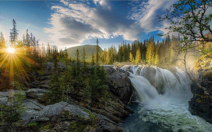 Waterfall in a forest with sunset sun rays