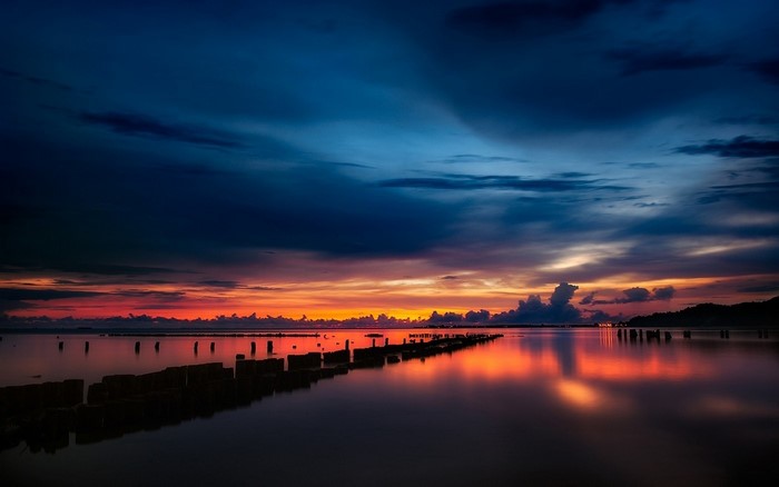 Sunset over the water with wooden posts