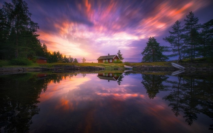 Sunset over lake with cottage and reflection