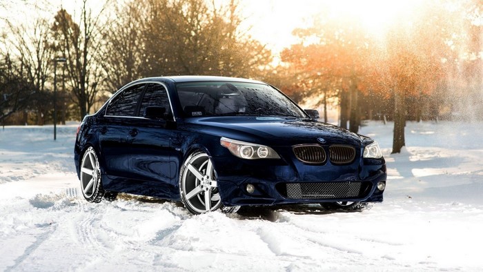 Dark blue BMW E60 5 Series in snow at sunset