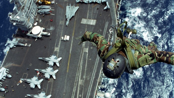 Paratrooper jumping from aircraft carrier with F-14 Tomcat and F/A-18 Hornets