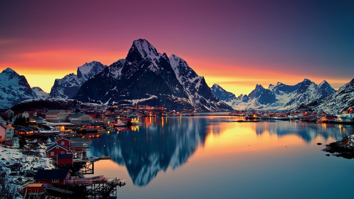 Village and mountains reflected in a lake at sunset