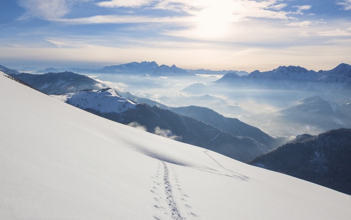 Snowy mountain landscape with footprints and mist