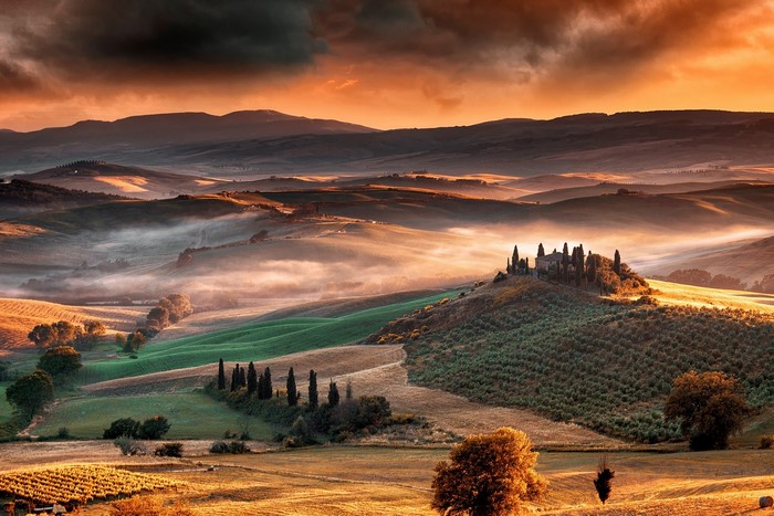 Tuscan landscape with rolling hills and a villa at sunrise