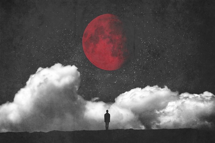 Silhouette of a person under a red moon and clouds