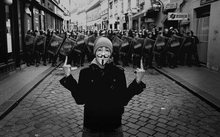 Guy Fawkes mask protester facing riot police