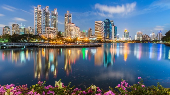 Bangkok skyline with lake and flowers at dusk