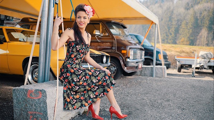 Woman in floral dress and red heels sitting outdoors