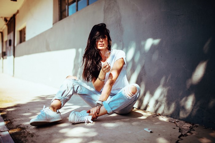 Woman in torn jeans smoking outdoors