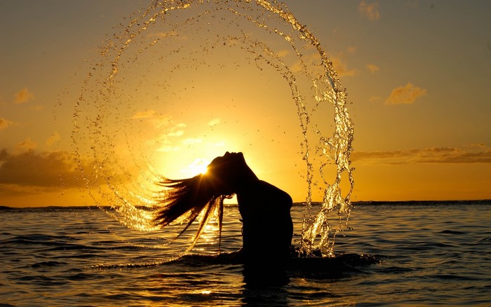 Woman splashing water at sunset