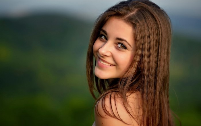Young woman with brown hair smiling outdoors