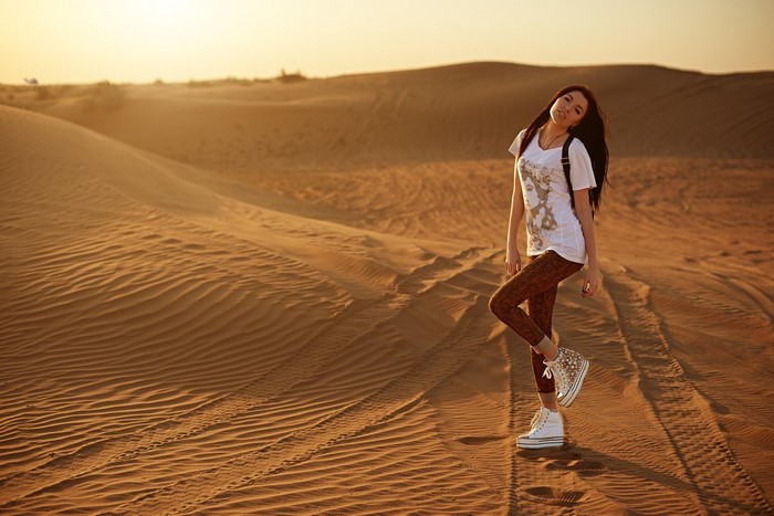 Woman posing in a desert at sunset