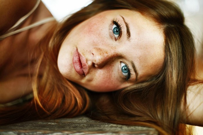 Woman with blue eyes and freckles lying down