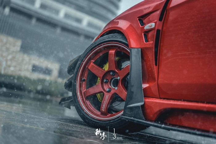 Red Mitsubishi Lancer Evo X with Volk Racing wheels in rain