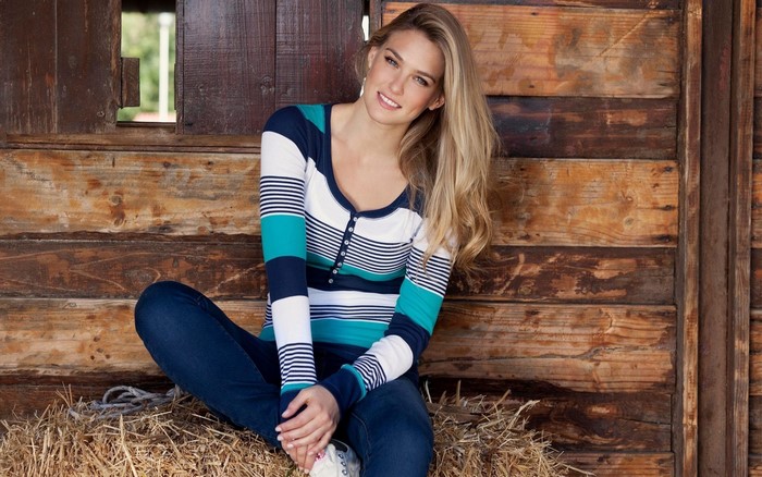 Bar Refaeli sitting on hay bale in barn