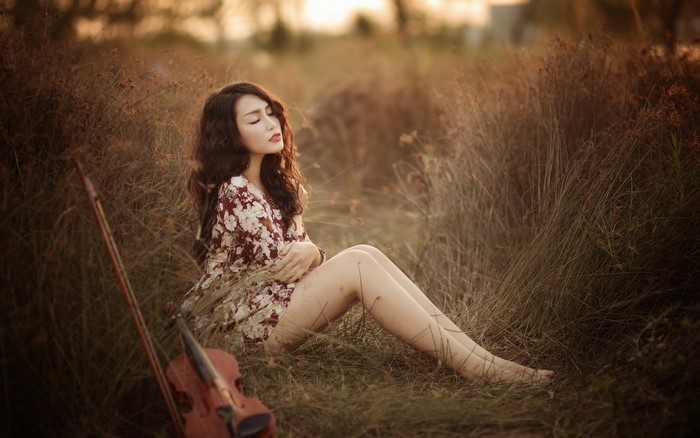 Woman sitting in a field with a violin