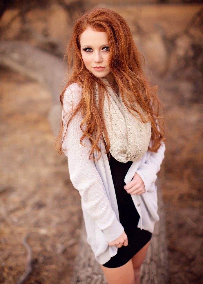 Redhead woman in black dress and white cardigan outdoors