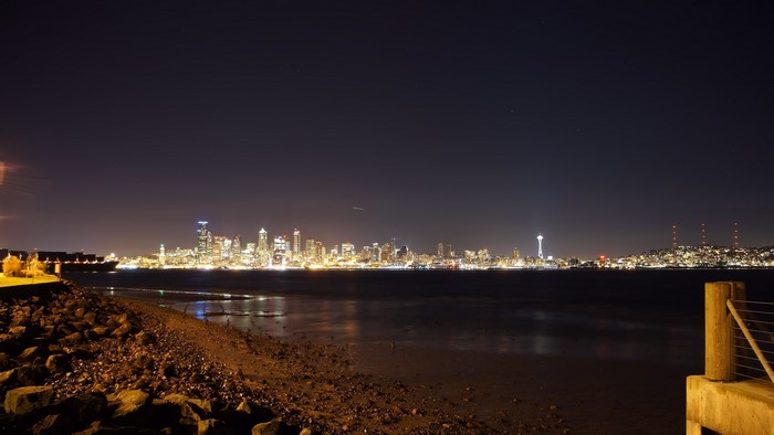 Seattle skyline at night from a rocky beach