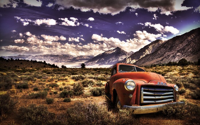 Old GMC truck in a desert landscape with mountains