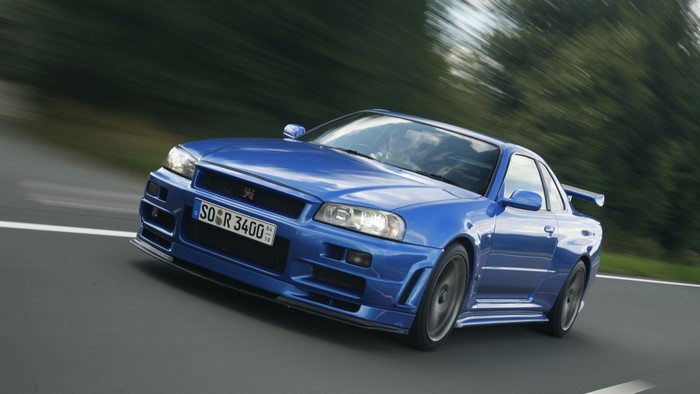 Blue Nissan Skyline GT-R R34 driving on a road