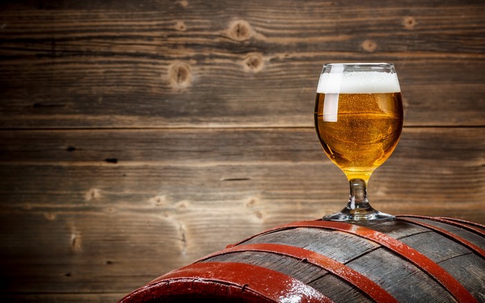 Glass of beer on a wooden barrel