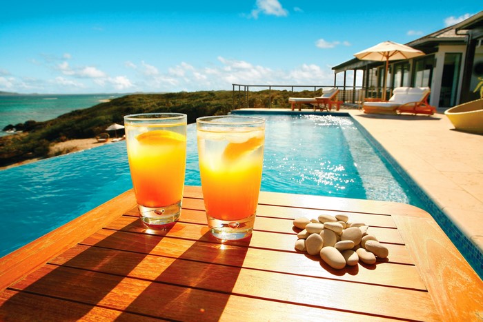 Two tropical drinks by an infinity pool overlooking the ocean