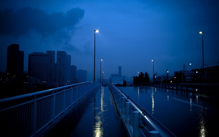 Rainy city street at night with streetlights
