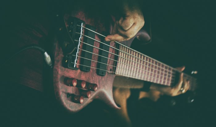 Close-up of a six-string bass guitar being played