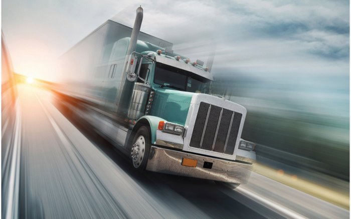 Turquoise semi-truck driving on a highway