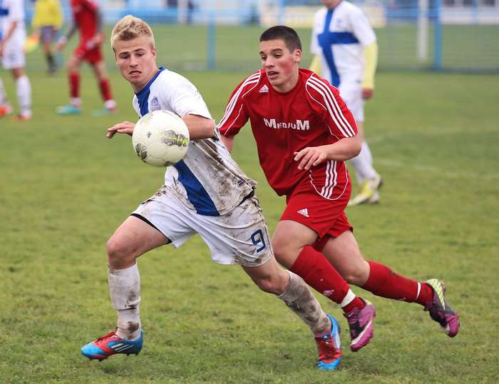 Two young male soccer players competing for the ball on a grass field