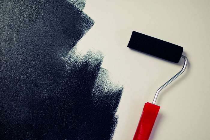 Painting a wall with a black roller