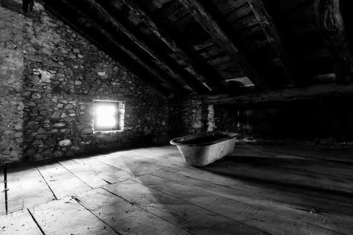 Old attic with bathtub and stone wall
