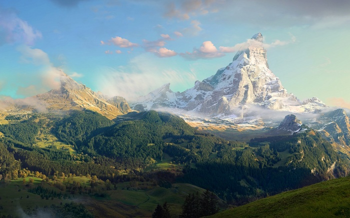 Snow-capped mountains and green valleys under a cloudy sky