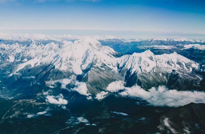 Snow-capped mountains under a blue sky with clouds