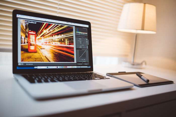 MacBook Pro with photo editing software and tablet
