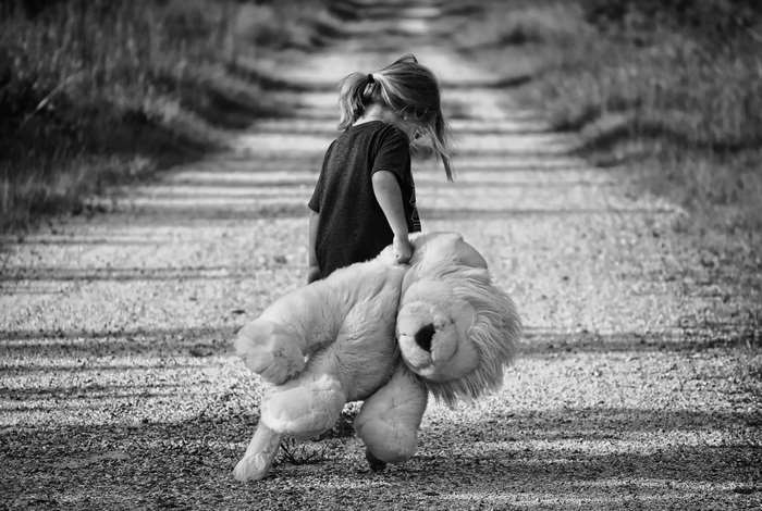 Child Walking Down Dirt Road with Large Teddy Bear