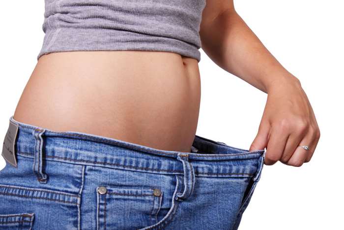Woman in loose jeans showing weight loss