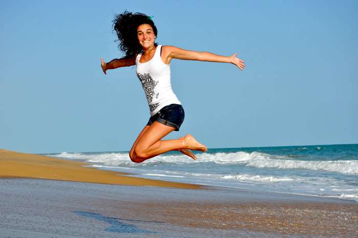 Woman jumping on a beach with ocean waves
