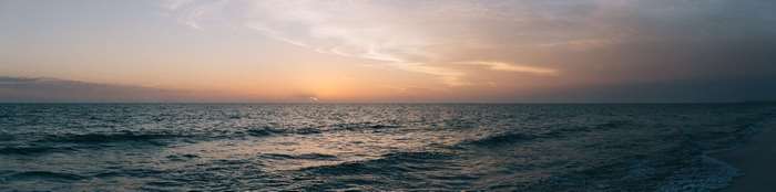Panoramic ocean sunset with waves and clouds
