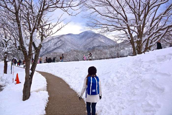 Girl with blue backpack in snowy landscape with mountains