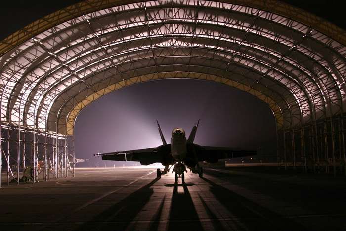 Fighter jet parked inside a hangar at night