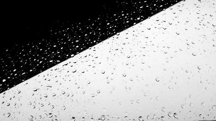 Raindrops on a window with black and white contrast