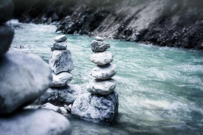 Balanced Stone Cairns by Flowing River Water
