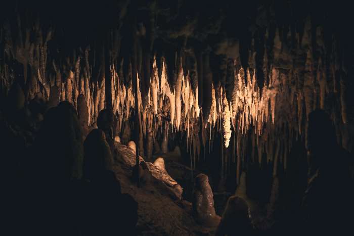 Cave with stalactites and stalagmites in darkness 4K