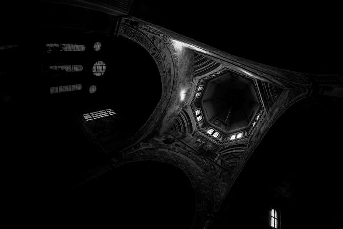 Interior of a dark church with ornate ceiling and windows
