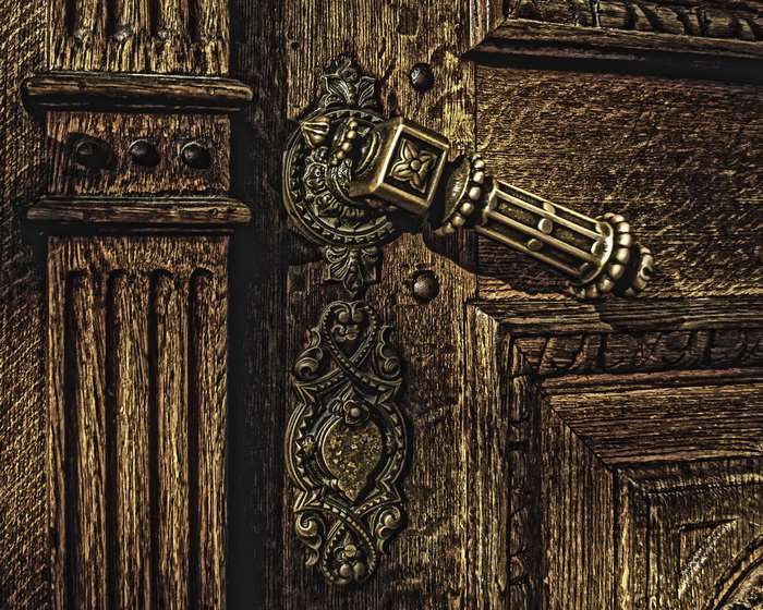 Ornate brass door handle on a weathered wooden door