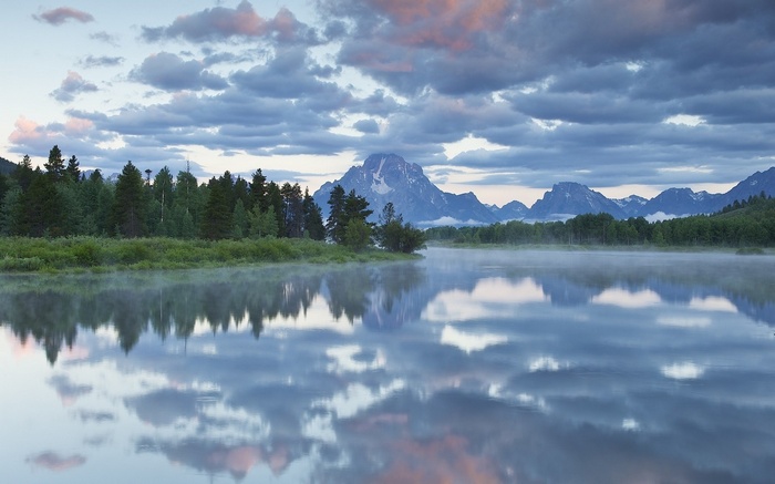 Mountains reflected in a misty lake at sunrise