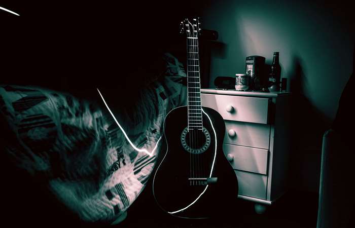 Acoustic guitar in a dark room with a dresser